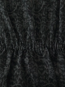 Nahaufnahme von grauem bedrucktem Stoff mit Taillenraffung und Vintage-Mustertextur