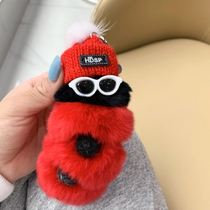 Detail of red plush caterpillar keychain with knitted hat and stylish sunglasses