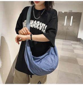 Détail du grand sac messager en nylon bleu porté par un mannequin pour le style urbain