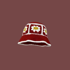Detail of red crochet bucket hat with handmade white and yellow daisy floral patterns