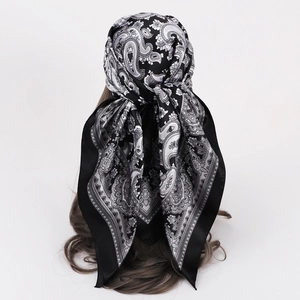 Detailed view of paisley print satin headscarf with black borders on white background
