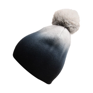 Detail of gradient tie-dye knit beanie with large fur pompom and ribbed cuff