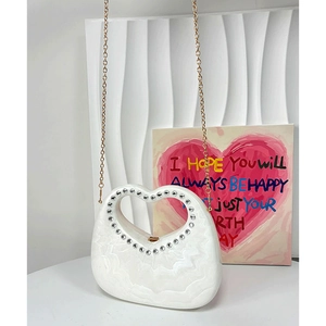 White heart-shaped handbag with marble texture, gold chain and rhinestone handle detail