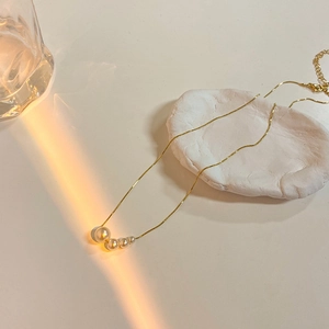 Détail du collier plaqué or avec quatre perles dégradées sur une chaîne délicate