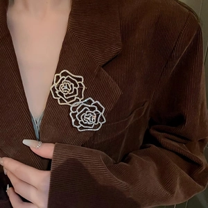 Detailed view of layered flower brooch with rhinestones on a corduroy suit lapel