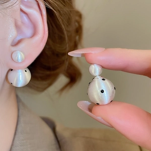 Detail view of 18k gold plated silver double ball earrings with black polka dots