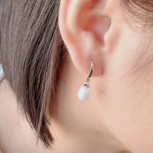 Macro shot of an elegant white drop pearl earring worn by a model in a minimalist style