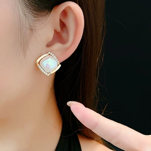 Vue rapprochée de boucles d'oreilles carrées en zirconium doré portées par un mannequin