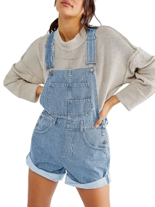 Detail of light blue denim overalls with multiple pockets paired with a beige knit sweater