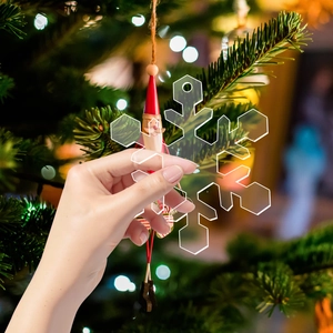 Close-up of clear acrylic snowflake ornament with pre-drilled hole on a Christmas tree
