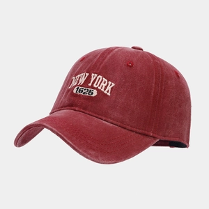 Detail shot of the 3D white NEW YORK embroidery on a vintage washed burgundy baseball cap