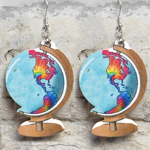 Detailed view of handmade globe earrings with wooden base on light stone wall background
