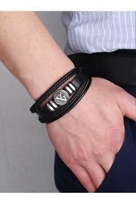 Détail d'un bracelet multicouche en cuir noir tressé pour homme porté sur un poignet