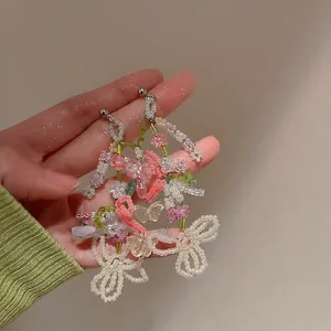 Detailed close-up of colorful butterfly and floral beaded tassel earrings with pastel stones