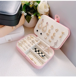 Detail of pink, black, beige and white portable jewelry boxes with layered compartments