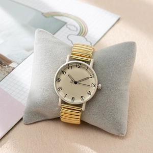 Detail of vintage gold stretch strap watch with Arabic numeral dial on velvet pillow