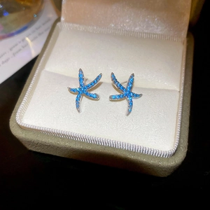 Detail of blue crystal starfish stud earrings with silver needle in a jewelry box