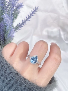 Macro view of teardrop blue sapphire ring with twisted band on lavender silk background