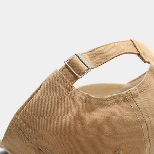 Detailed macro view of the adjustable metal buckle on a khaki cotton baseball cap