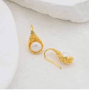 Detail of bird nest design earrings with natural freshwater pearls and gold plating