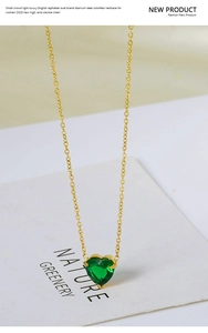 Detailed close-up of 18k gold titanium steel necklace with heart-shaped green zircon