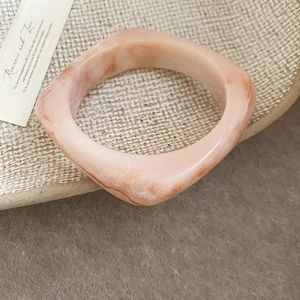 Detailed macro shot of square pink marble resin bangle with elegant swirling texture