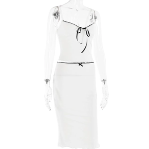 Close-up of white two-piece set featuring lace trim and black bow details with ruffles