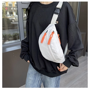 Detail of white nylon chest bag featuring vibrant orange zipper pulls and plastic buckle
