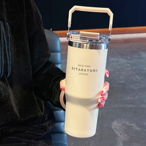 Insulated cream coffee mug with wide handle and straw in a cozy home setting