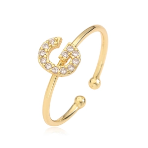Macro detail of gold-plated open ring featuring a G-letter pavé set with tiny zircons