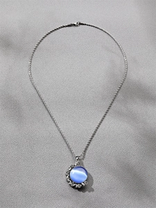 Vue détaillée d'une chaîne argentée torsadée avec pendentif œil de chat bleu et cristaux