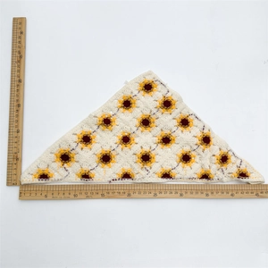 Flat lay of a white crochet head scarf with sunflower patterns showing size measurements