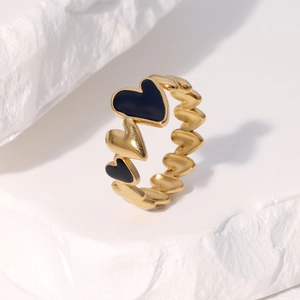 Minimalist gold and black enamel heart ring on white stone background with open design