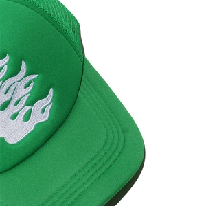 Detailed close-up of white flame embroidery on the green mesh trucker hat brim