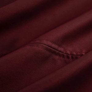 Macro shot of double-needle stitching on deep wine red coat fabric with fine texture