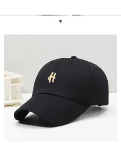 Detail of black cotton baseball cap with gold H embroidery and curved brim structure