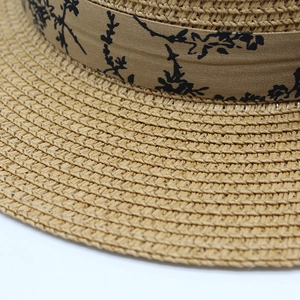Close-up of natural straw weave texture and elegant floral ribbon on wide brim summer sun hat