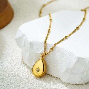 Détail du pendentif goutte en or 18 carats avec gravure étoile et zircon sur chaîne perlée