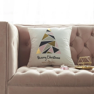 White Christmas pillow cover with geometric tree and golden Merry Christmas text on sofa