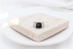 Macro detail of polished silver signet ring with a black square top on stone pedestal