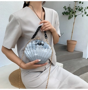 Detail of gradient grey shell-shaped acrylic bag featuring a stylish black chain handle
