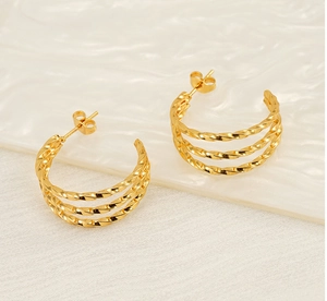 Detail of gold multilayer twisted hoop earrings with layered cable texture and butterfly back