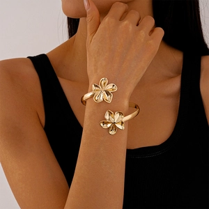 Détail d'un bracelet de bras doré poli avec deux charmes de fleurs de frangipanier