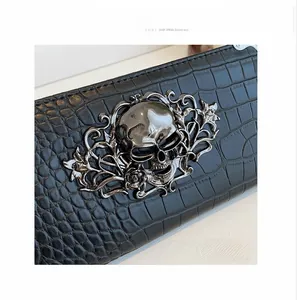 Detail of black crocodile texture leather wallet with a silver metal skull ornament