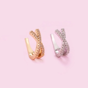Detail of cross-shaped ear cuffs in rose gold and silver with shimmering micro-pave zircons