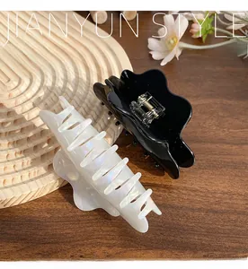 Close-up of wavy black and pearl white hair claws on a wooden tray with flowers