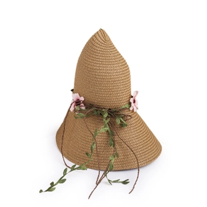 Detail of bohemian straw hat with pink flowers, green vines, and natural woven texture