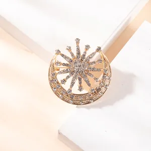 Macro detail of crescent moon and sunburst brooch with inlaid rhinestones on gold alloy