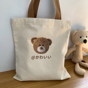 Close-up of a cream canvas tote bag featuring a cute brown teddy bear print and text