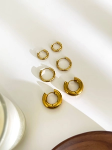 Macro view of three sizes of high-polished gold hoop earrings in a minimalist stack